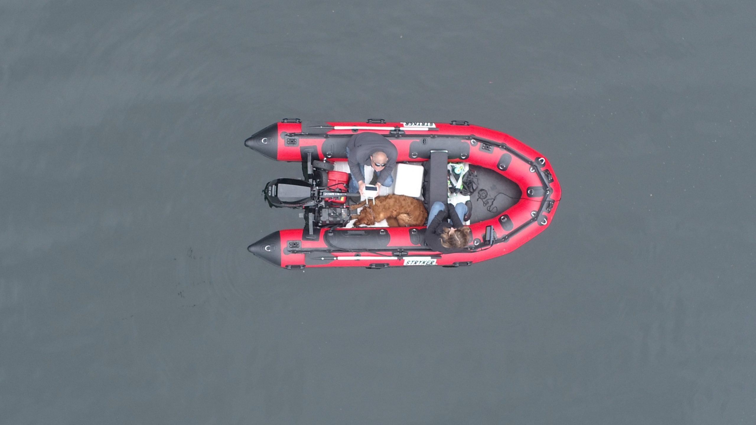 couple with their dog in a red inflatable boat