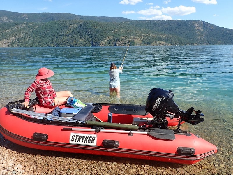 fishing lakeside in a red inflatable boat