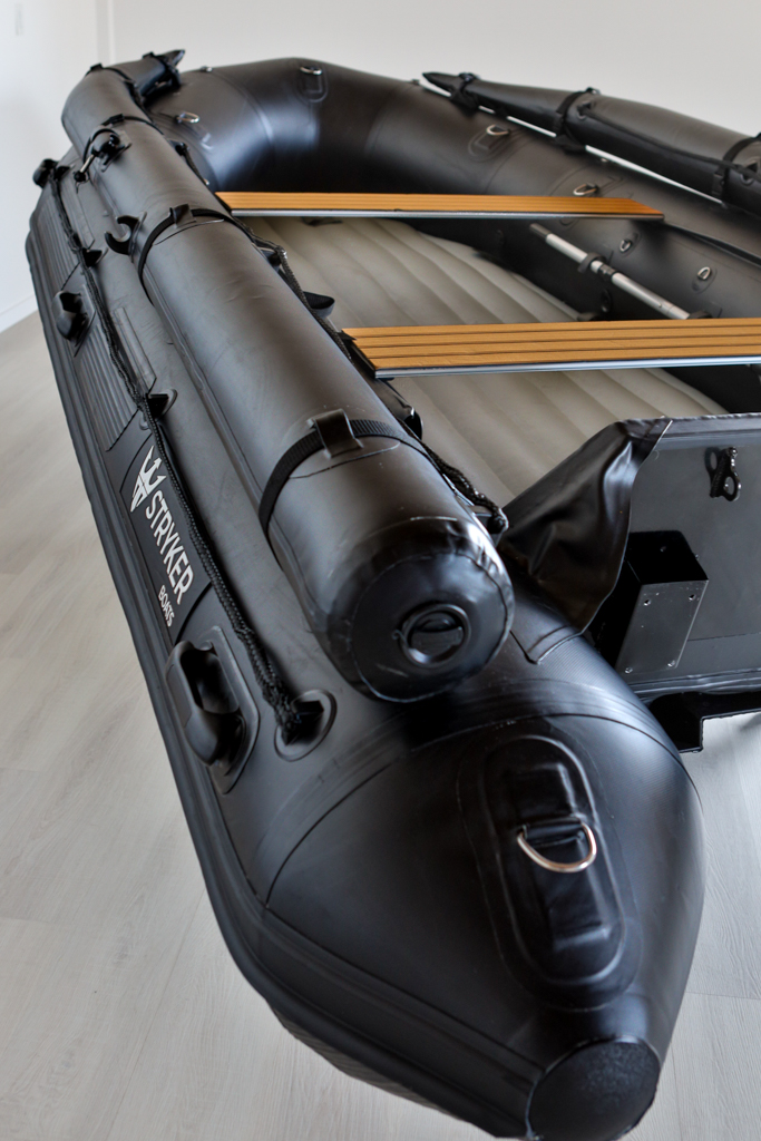 stealth black inflatable jet boat in showroom with a close up of top tubes