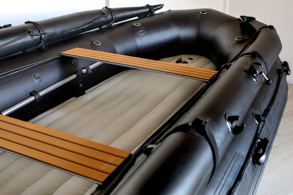 stealth black inflatable jet boat with inflatable floor in showroom with a close up of top tubes